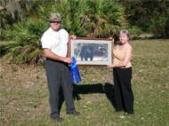 Florida Panther Project spokesman Bill Samuels presents Myakka Valley resident Margaret Cooper with her Black Leopard painting entitled "Mystic Realm" by artist Charles Frace.  Margaret was the Grand Prize winner of the drawing held at the 2005 Sarasota County Fair